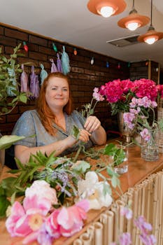 Woman florist crafting a vibrant flower arrangement behind a counter indoors.